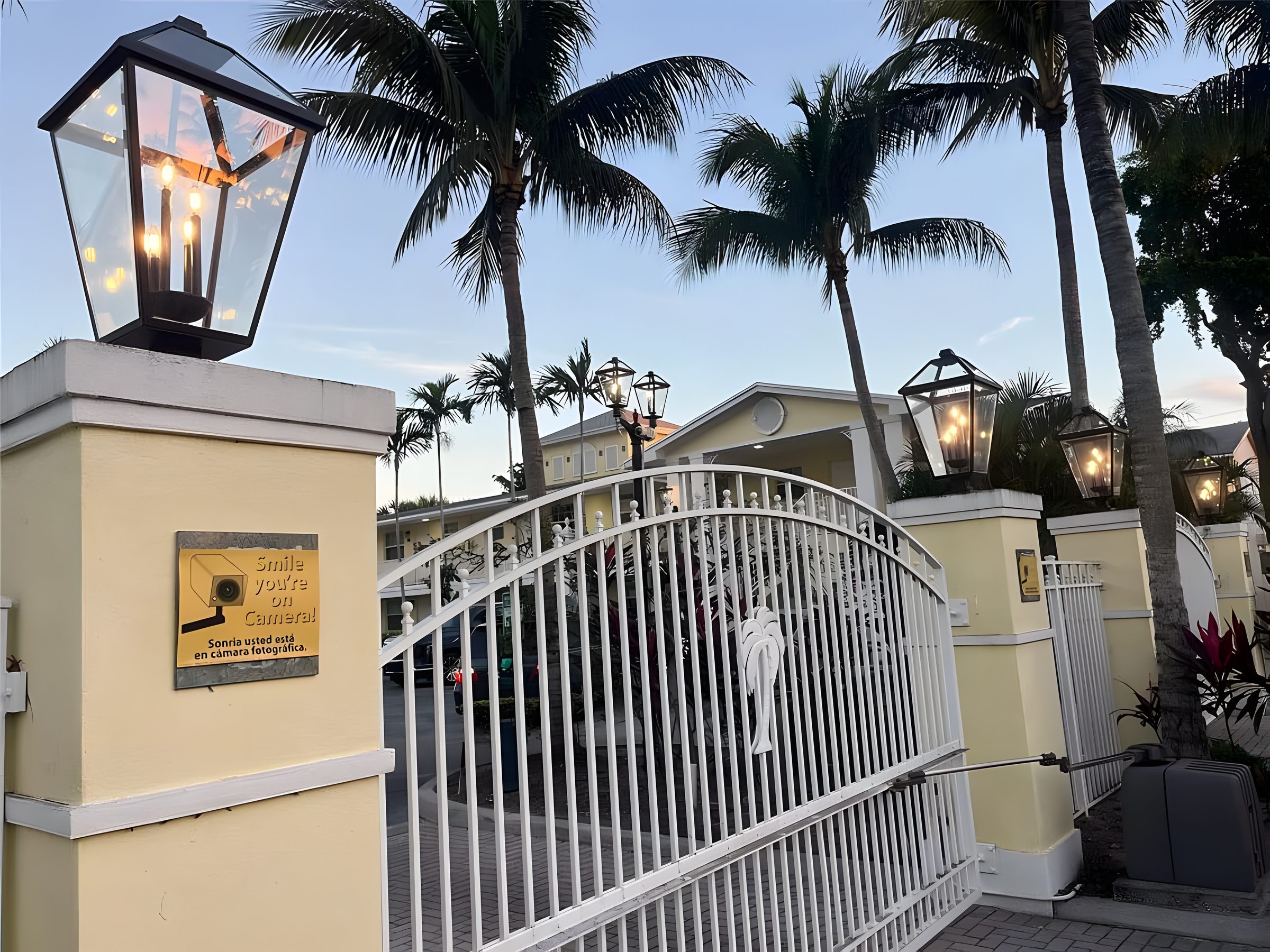 The gate at The Grove, lanterns on the piers and palms behind.